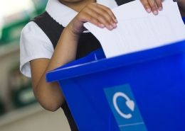 Girl putting paper in recycling bin