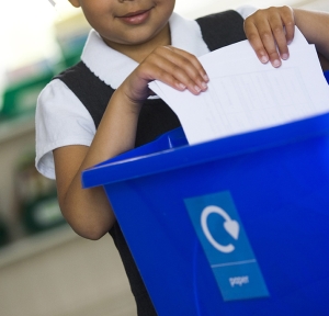 Girl putting paper in recycling bin