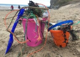 Child's plastic bucket on beach full of plastic litter