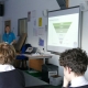 Waste Educator Lucy in front of a smartboard teaching about the circular economy in a GCSE class with backs of students heads