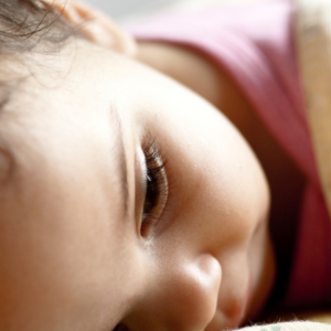 Child laying down and thinking with an up close focused image on her eye.