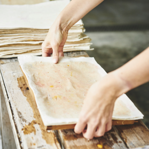 Picture of someone pressing down on recycled paper making frame