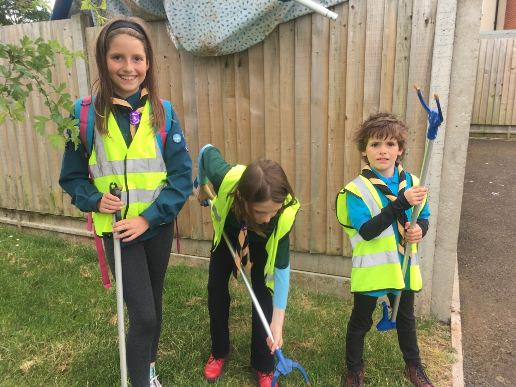 3 children in Scout, Cub and Beaver uniforms with litter pickers