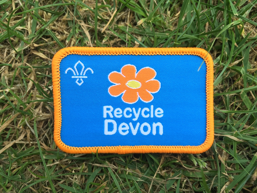 Close up of a Recycle Devon Scout Badge lying on grass