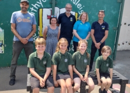 Children at Withycombe Raleigh Primary school sat on a bench, with representatives from their school, Resource Futures, Devon Contract Waste and the Ocean Recovery Project stood in a row behind them