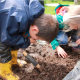 Image of two children with magnifying glasses looking in the mud for minibeasts
