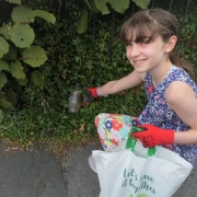 Girl picking up litter from a hedge wearing gloves