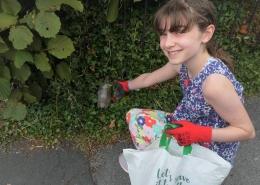 Girl picking up litter from a hedge wearing gloves