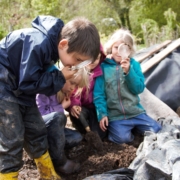 Children using magnifying glasses to study compost inan outdoor environment