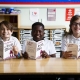 3 smiling children reading the book The Iron Man by Ted Hughes