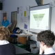 Waste Educator Lucy in front of a smartboard teaching about the circular economy in a GCSE class with backs of students heads