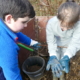 2 children wearing gloves and looking at minibeasts in a compost container