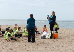 Waste educator on beach with class of children and teacher