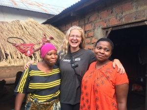 Annie in Tanzania smiling between two of her hosts in front of a house