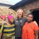 Annie in Tanzania smiling between two of her hosts in front of a house
