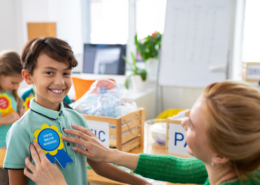 Teaching putting a badge on a child to reward them for their environmental efforts. It is the main picture for the Universal Children's Day post. This is a stock photo.