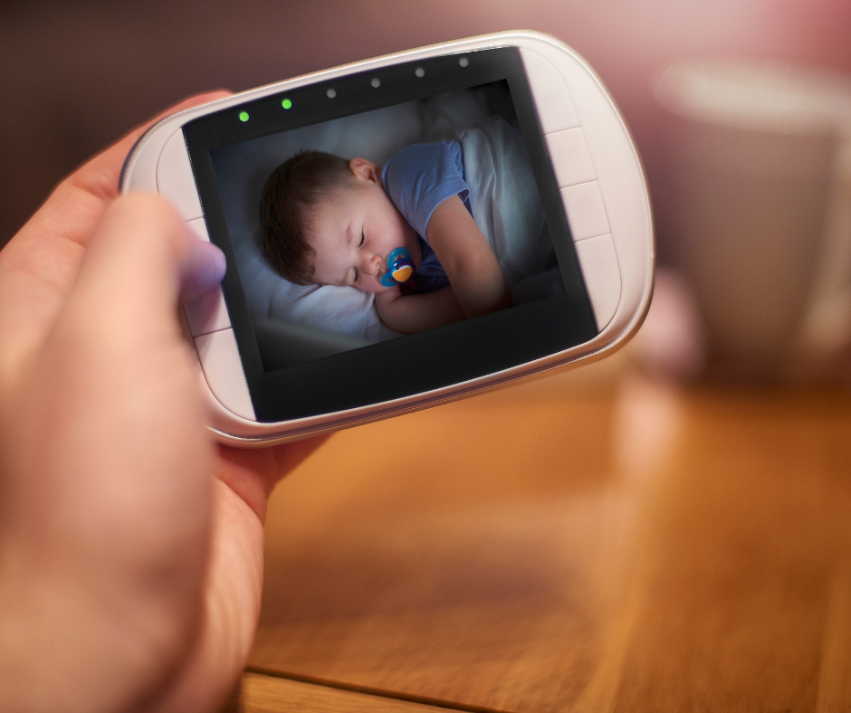 Image of baby sleeping on a baby monitor in a persons hand