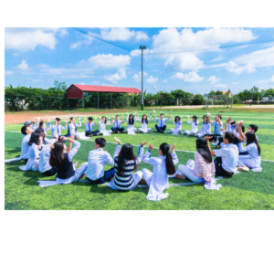 School pupils sat in a large circle in a field. It is a stock photo to empahsies child empowerment on Universal Children's Day