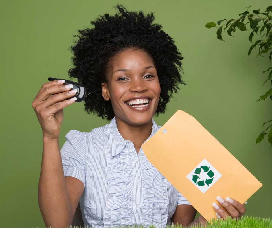 Image of a black woman putting an old mobile phone into a brown envelope to be recycled