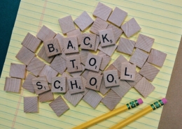 Scrabble letters arranged to spell out Back to School on a sheet of lined paper with two pencils