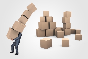 Man carrying a stack of 5 cardboard boxes, almost falling over with a pile of cardboard boxes behind