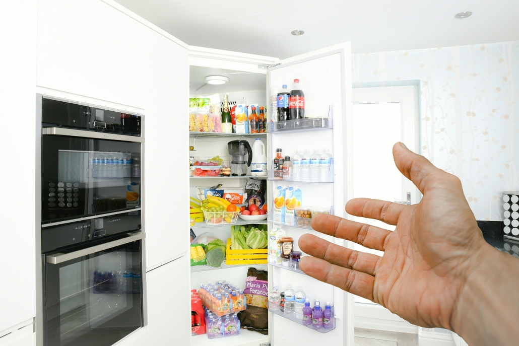 Image of an open white fridge full of fruit and vegetables and drinks in a kitchen