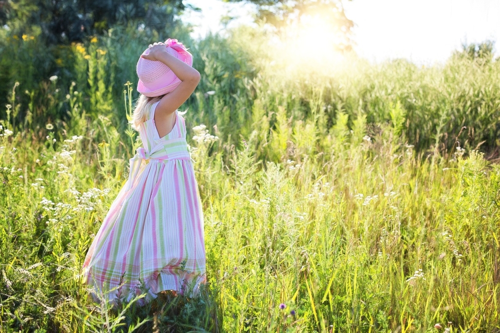 Sustainability Bulletin title picture of a little girl in a long dress bathed in summer sunshine standing with her back towards us in a field