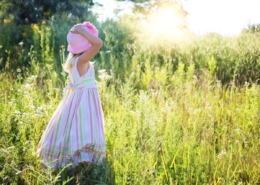 Sustainability Bulletin title picture of a little girl in a long dress bathed in summer sunshine standing with her back towards us in a field