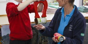 Child and waste educator Sally with magnet separating steel can from aluminium can