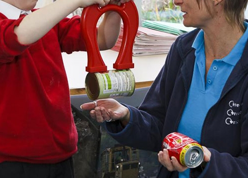 Child and waste educator Sally with magnet separating steel can from aluminium can