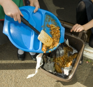 Plastic school canteen try being scraped into a bin of food waste