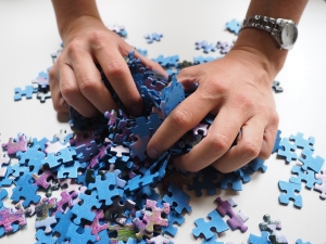Hands picking up puzzle pieces