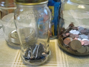 Glass jar with nails inside and another with pennies inside