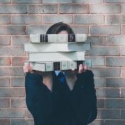 A girl holding up some books that covers her face