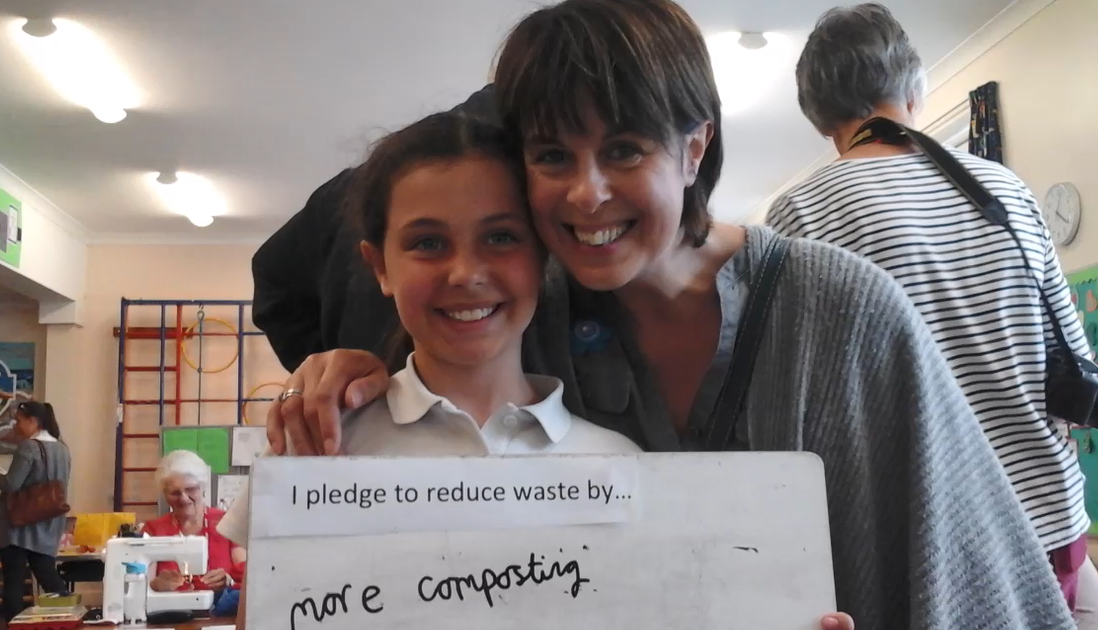 Child and parent holding up a pledge at St Peters Primary School Eco Fair