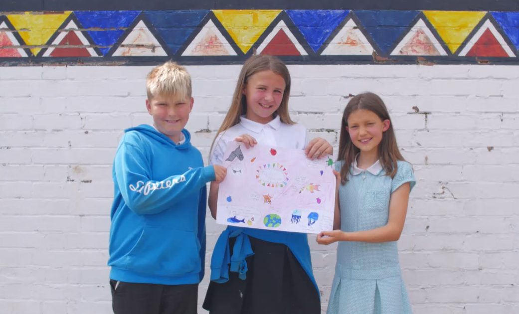 Smiling children holding up a poster