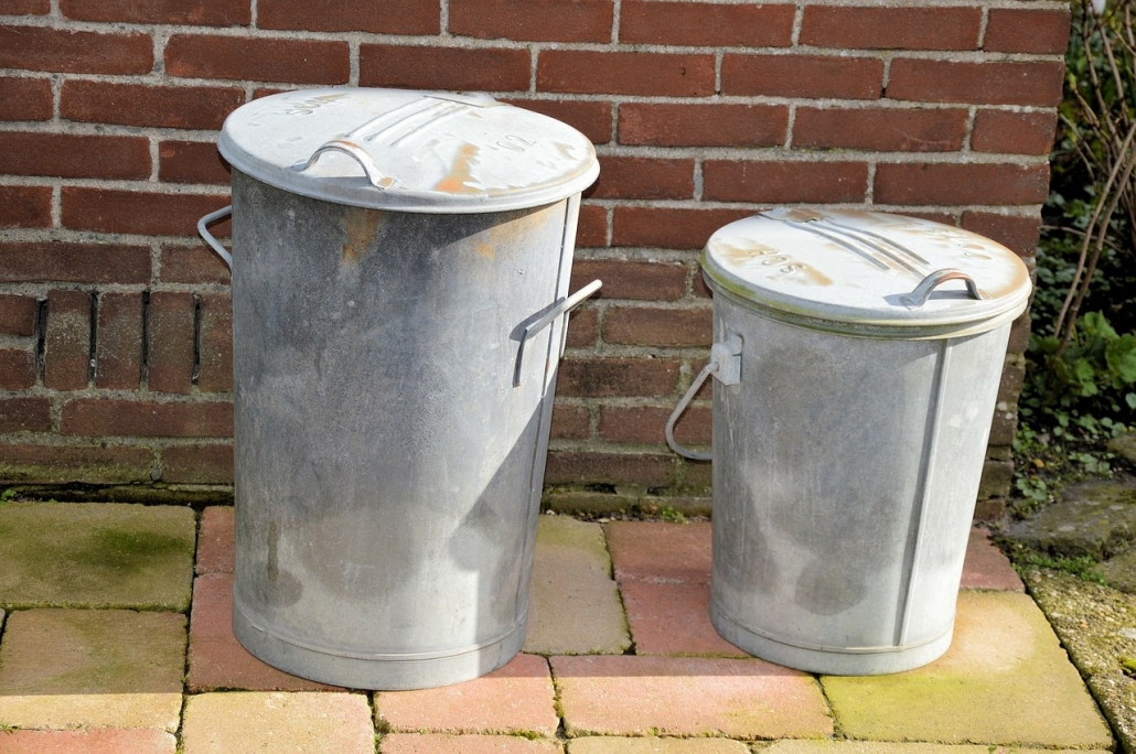 Two simple metal dustbins on a patio.