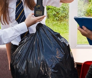 School pupil weighing black bin bag. The picture is to emphasises child empowerment theme with Universal Children's Day
